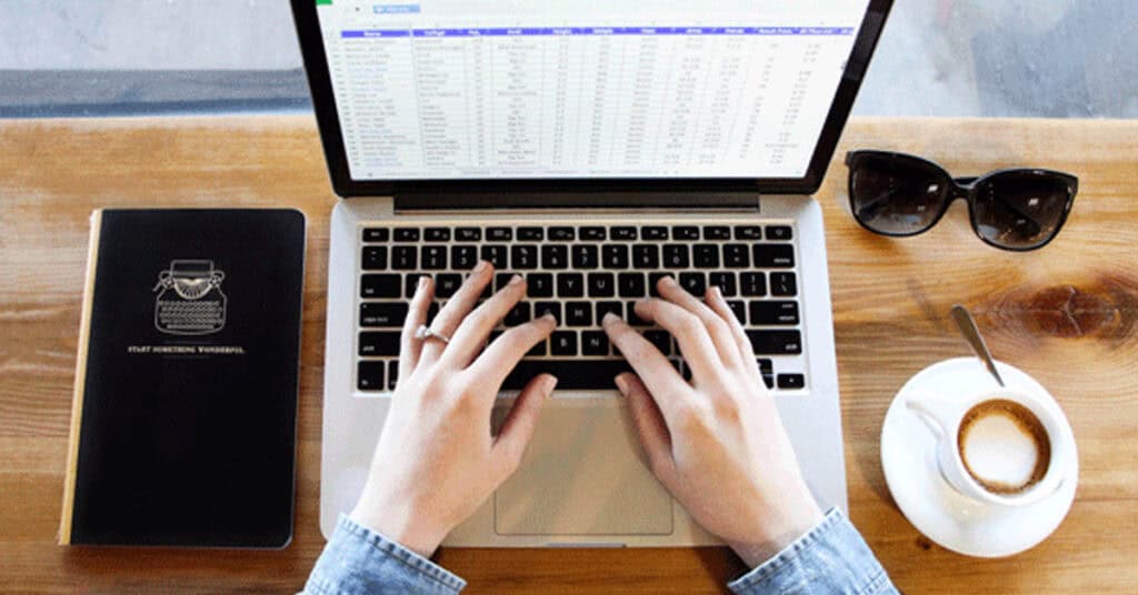 Laptop displaying Perimeter software on a wooden desk with coffee, sunglasses, and a notebook, emphasizing cybersecurity and business management tools for optimal SEO relevance.