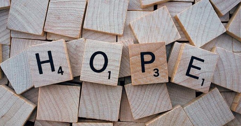H2O chemical formula spelled out with wooden Scrabble tiles on a pile of wooden blocks, representing water, hydration, and environmental sustainability.