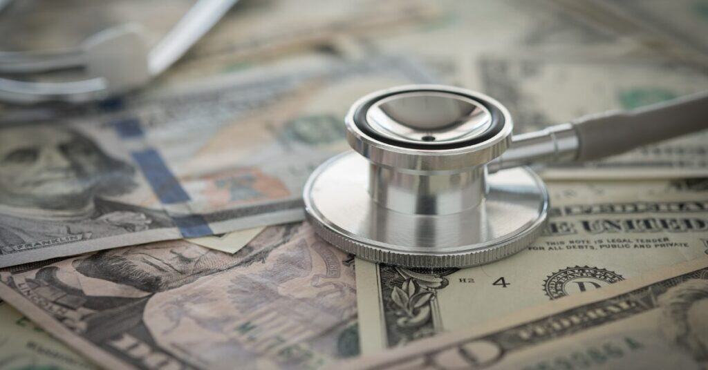 Stethoscope on cash dollar bills, healthcare and medical insurance payment concept.