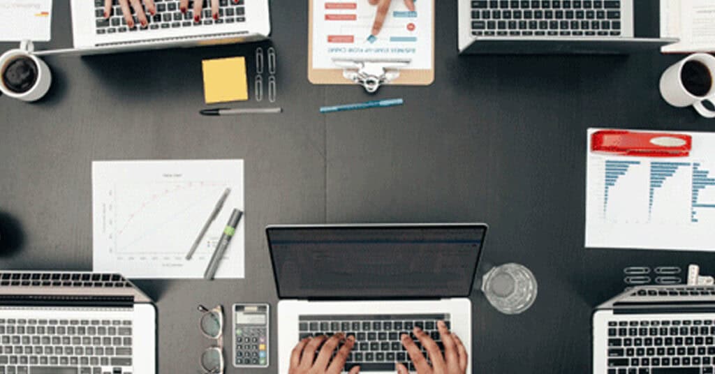 Efficient business team working on project at modern office desk with laptops and data charts.