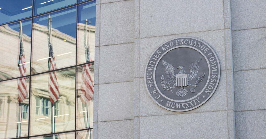 U.S. Securities and Exchange Commission logo on building wall with American flags reflected in glass windows, representing financial regulatory authority and compliance.