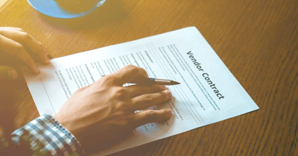 Vendor contract signing document on a wooden table for legal business agreements and partnerships.