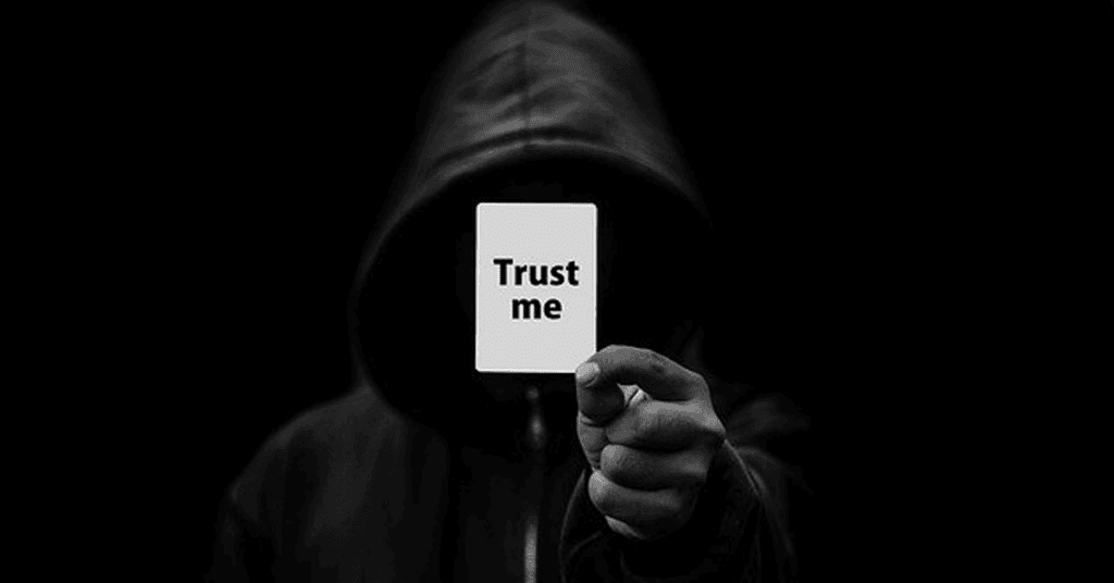 Trust me message card held by hooded figure in dark setting, emphasizing cybersecurity, trust, and digital security services by Perimeter.